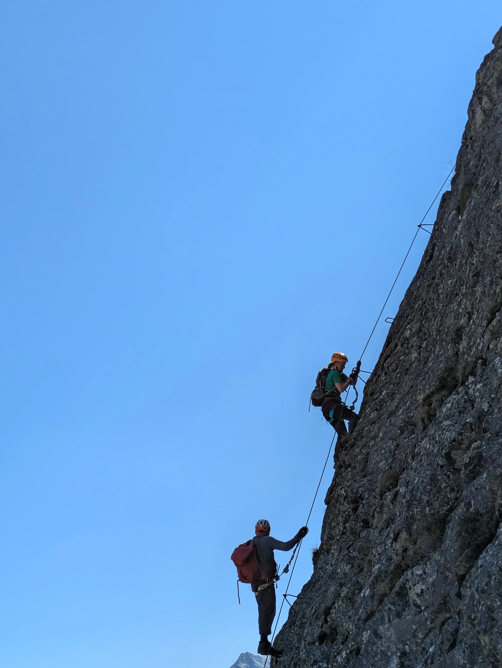 rechts felsige Wand an der zwei Männer mit Klettersteig-Ausrüstung hochklettern | © DAV Karlsruhe