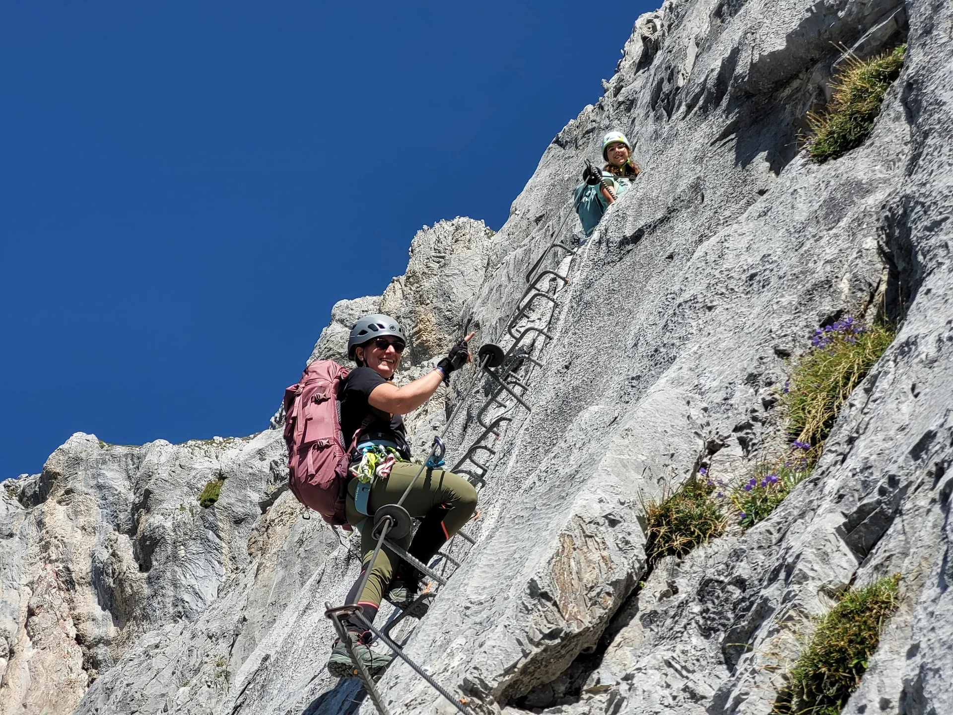 Foto von unten, wie zwei Personen Klettersteig-Tritte hochklettern | © DAV Karlsruhe