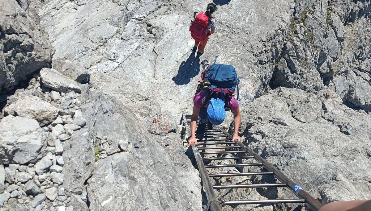 Metalltreppe in Felswand von oben, Bergsteigerin klettert hinauf | © DAV Karlsruhe